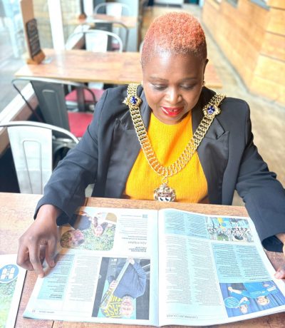 The Lord Mayor of Canterbury Cllr Keji Moses is seated and reading an open edition of the Canterbury Courier
