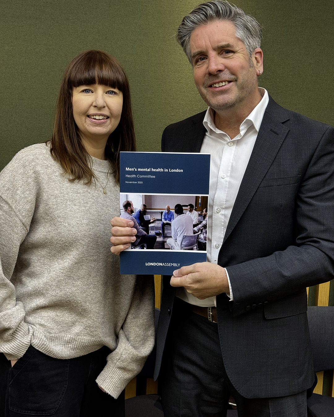 Dr David Palmer stood holding the reports, with Lucy Dodd (Mind Strategic Lead) at the launch of London Assembly’s new mental health report in November