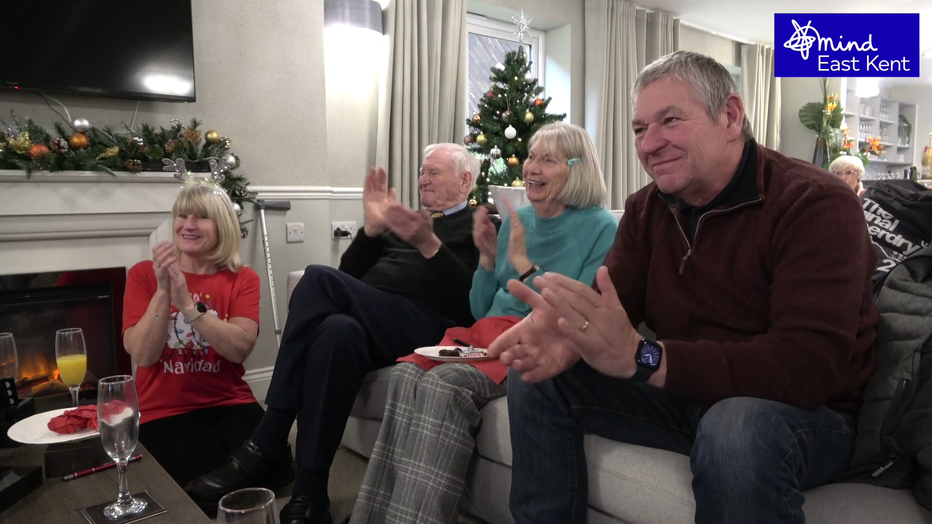 A group of veterans applauding and smiling while seated at the Christmas party organised by the Veterans Project in East Kent