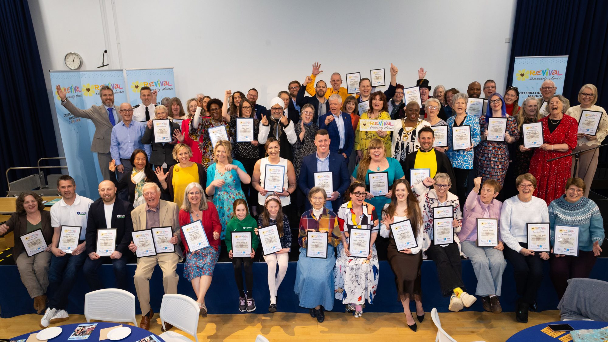 The groups of winners facing the official photographer smiling and cheering and holding either their winners or champions certificates