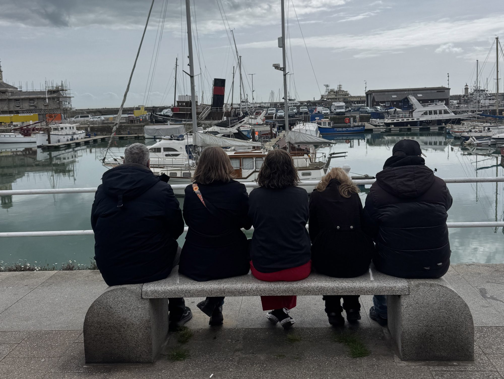 Five members of our Ramsgate wellbeing walks groups sit with their back to the camera and gaze out over Ramsgate harbour