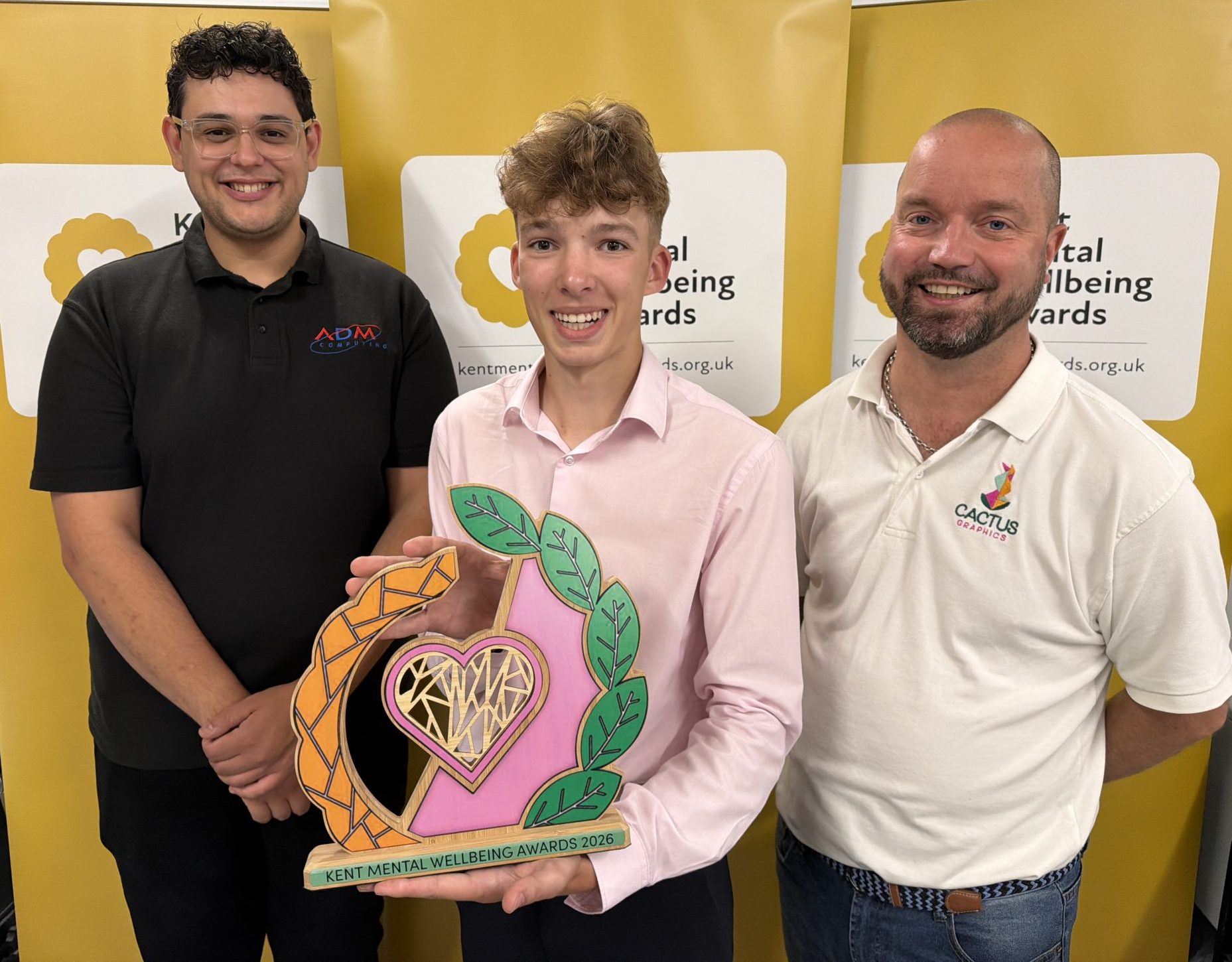 Henry Ross holds his winning trophy design watched by event judges